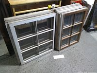 Two stacks of six-pane wooden window sashes showing both sizes and finishes