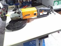 Full view of angle grinder on table showing body, guard, handle, power cord