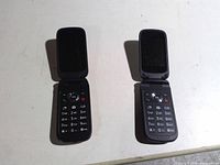 Both flip phones open showing keypads and screens