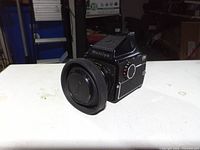 Front left view of camera showing lens, hood, cap and prism finder