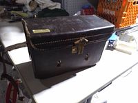 Dark brown leather camera case with brass latch and broken strap