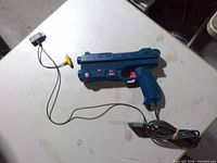 Full view of Nuby Sniper light gun with cable and adapter on table
