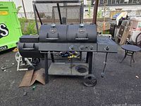 Full view of Oklahoma Joe's smoker grill combo showing three main lids, control knobs, side firebox, wheels, and shelf