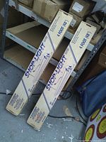 Two boxed 4-ft Shop-Light fixtures on shelf