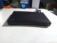 Front view of Samsung Blu-ray player showing disc tray, USB port and power buttons