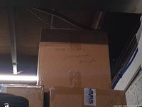 Outer carton labeled "Shoe Covers Universal 100/pk" stacked in storage area