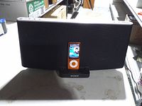 Front view of Sony speaker dock with orange iPod Nano docked
