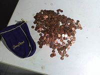 pile of assorted US pennies next to purple Crown Royal bag