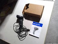 Scanner with coiled USB cable, box and guide on table