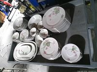Overall view of stacked dinnerware showing plates, bowls, platters with floral pattern