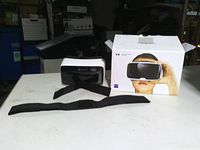 Front view of Zeiss VR One Plus headset with strap and box