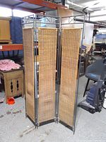 Front view of three-panel wicker and metal room divider standing upright