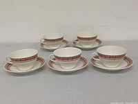 Five cup and saucer sets displayed facing camera