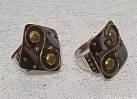 Front view showing brass swirl and studs on oxidized silver faces