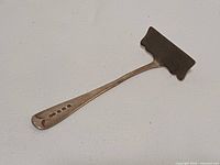 Front view of sterling silver baby food pusher highlighting blade and hallmarks on handle