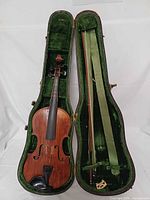 Open case showing violin, two bows, bridge and green velvet interior