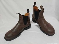 Oblique view of both boots showing leather uppers, side gores, and outsole condition