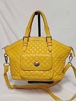 Front view of yellow quilted leather satchel showing flap pocket with turn-lock and detachable strap