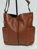 Front view of brown pebbled leather crossbody showing key charm, center seam, side pockets
