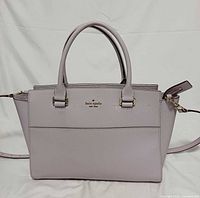 Front view of satchel showing overall design, handles, strap and exterior pocket