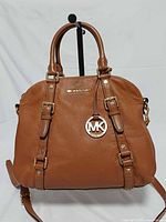 Front view of Michael Kors Bedford brown leather satchel with handles, strap, gold hardware and MK charm visible