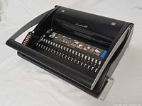 Top and front view of binding machine showing comb slot and control panel