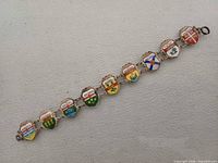 Full view of bracelet laid flat showing all nine enamel shield links and clasp