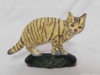 Front view of cast iron tabby cat doorstop on green base