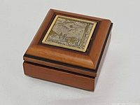 Closed wooden box showing silver relief plaque on lid