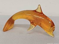 Side view showing amber body and clear fins of dolphin figurine