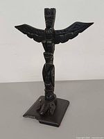 Front view of argillite Haida totem pole showing overall form and chipped base corner