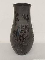 Front view of black clay vase showing deer and sunburst motifs