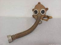 Full view of tan gas mask and hose
