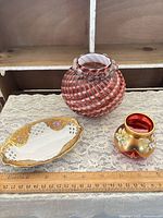 Group shot showing cranberry vase, bud vase, porcelain dish with ruler for scale
