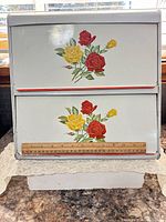 Front view showing two doors, floral decals, ruler for scale