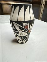Front view of black clay vase showing geometric and figural designs