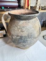 Front view of terracotta pitcher showing rim, body shape, incised bands, surface wear