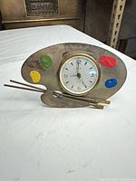 Front view of brass artist palette clock with paint accents and brushes
