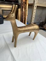 Side profile of brass antelope sculpture showing overall form and ribbed texture