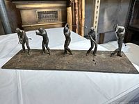 Full view of bronze sculpture with five golfer figures on base