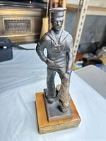 Full view of bronze sailor figurine on wooden base