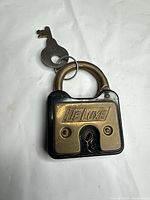 Front view DeLuxe brass padlock with key attached