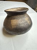 Full view of earthenware jar showing shape, mouth, and incised bands
