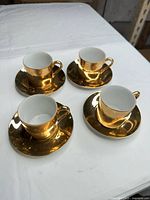 Complete set of four gold cups on matching saucers
