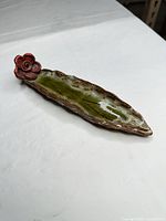 Full view of elongated green glazed ceramic leaf tray with red flower accent