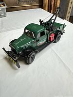 Front three-quarter view showing green Dodge Power Wagon diecast wrecker with plow blade, tow boom, OSH livery