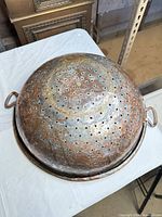 Top view of large perforated copper colander showing overall size and hole pattern