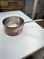 Side view of saucepan showing copper exterior and brass handle