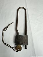 Full view of padlock showing long shackle, key attached by string