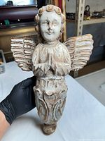 Full frontal view of carved wooden angel being held, showing overall form and finish